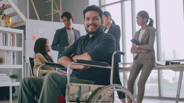 A disabled company employee is able to work happily with colleagues in the office. A disabled company employee is able to work happily with colleagues in the office. disabled sign stock pictures, royalty-free photos & images