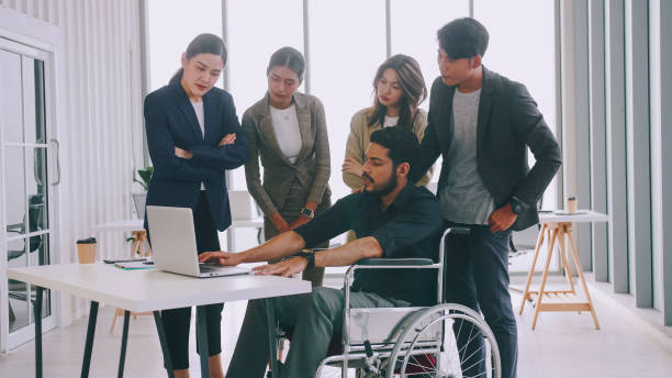 istock A disabled company employee is explaining a computer program to a group of colleagues. 1408174018