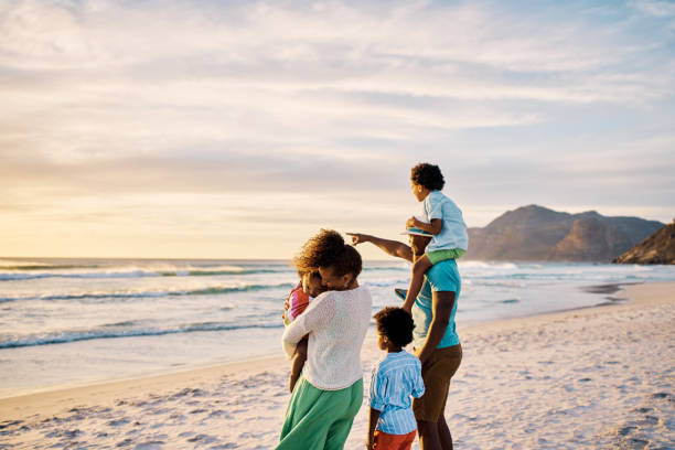Copy space with a family on the beach admiring the scenic sunset view and calm waves from behind during a fun summer vacation together. Loving parents bonding and relaxing with their little cute kids copia el espacio con una familia en la playa admirando la vista panorámica del atardecer y las olas tranquilas desde atrás durante unas divertidas vacaciones de verano juntos. padres amorosos que se unen y se relajan con sus pequeños y lindos hijos