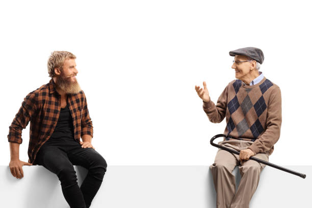 istock Elderly man talking to a bearded guy seated on a white panel 1408176252