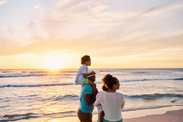 istock A family bonding on the beach while relaxing at sunset during fun summer vacation and getaway together. Loving parents relaxing with their little kids and enjoying a break to travel 1408177303