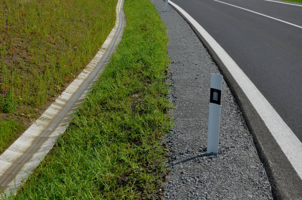 rury kanalizacyjne pod mostem. przejście przez rów boczną drogą. betonowy otwór z kamiennym otoczeniem chodnikowym. rynna spływa wokół drogi i jest pełna czystej wody, nowego asfaltu, krawędzi, żwiru - seat row obrazy zdjęcia i obrazy z banku zdjęć