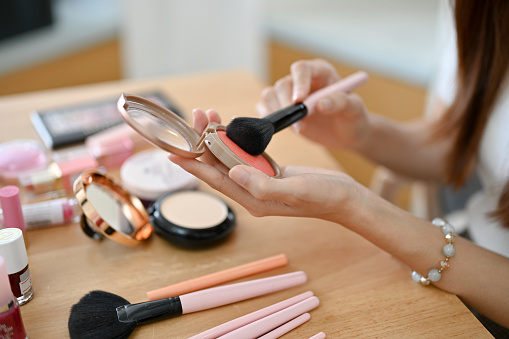 Pink blush and brush in hands of woman
