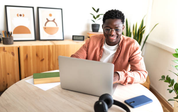 happy black male university student studying at home using laptop. - student college student computer university imagens e fotografias de stock