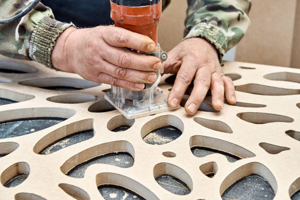istock Decorative partition wall with floral pattern. Carpenter milling holes in MDF with a hand electric router machine 1408185210