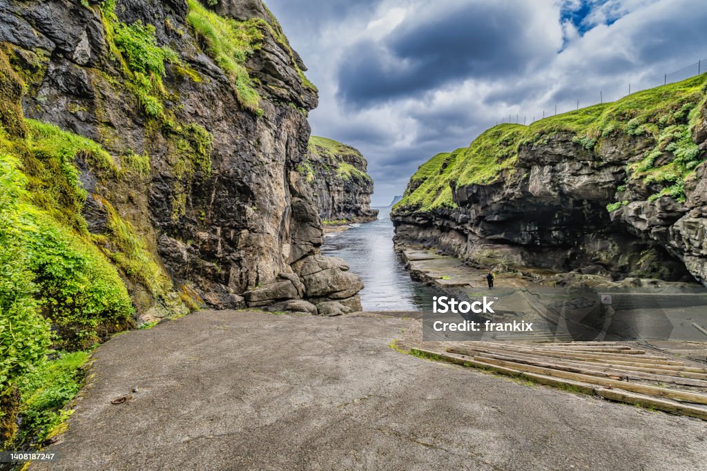 Gjógv gorge harbour, situated on the slope of the mountain on Eysturoy island with Traditional wooden houses, Faroe islands Gjógv gorge harbour, situated on the slope of the mountain on Eysturoy island with Traditional wooden house - Faroe islands Cliff Stock Photo