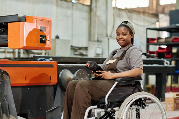 istock Worker in wheelchair in factory on the machine 1408192032