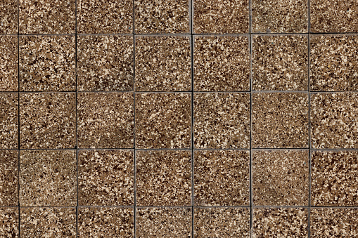 Section of a wall with brown mottled tiles.