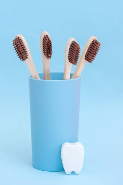 istock Bamboo toothbrushes and a white tooth on a blue background. Vertical photo. 1408194148