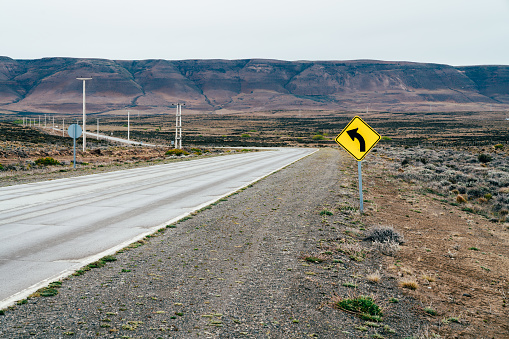Empty road in Patagonia with a yellow sign. Patagonian road in the middle of nowhere on the way from El Calafate to El Chalten.