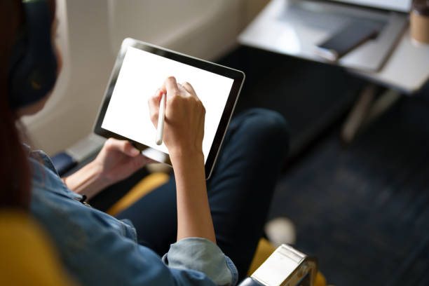 istock An Asian woman sits in a window seat in Economy Class using a white screen tablet that can use text or advertising while flying. Travel, vacation, vacation ideas 1408199900