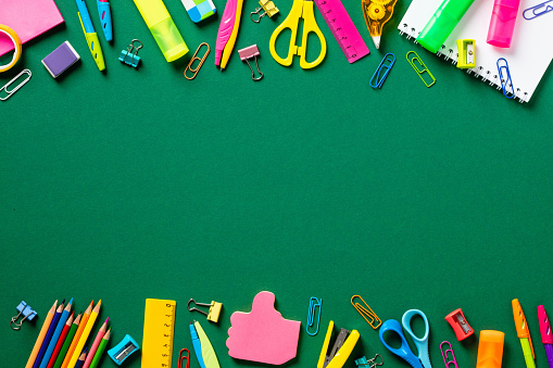 Back to school concept. Creative layout with colorful school supplies on green background. Flat lay, top view, copy space