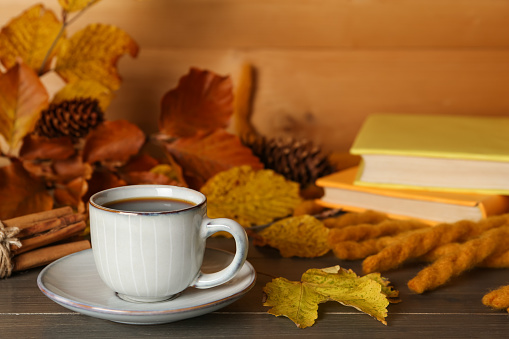 Composition with cup of hot coffee and autumn leaves on wooden table. Space for text