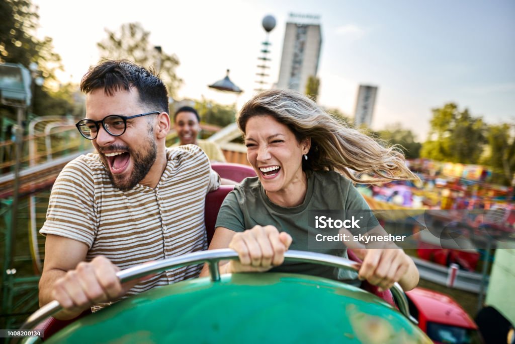 Young cheerful couple having fun on rollercoaster at amusement park. Cheerful couple having fun while riding on rollercoaster at amusement park. Rollercoaster Stock Photo