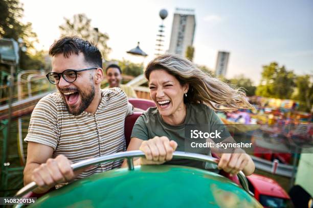 Young Cheerful Couple Having Fun On Rollercoaster At Amusement Park Stock Photo - Download Image Now