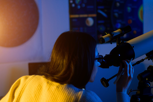 Astronomer woman looks through telescope at night sky, space, cosmos, universe, Milky way. Female scientist watching the stars and Moon with professional telescope at a summer day. Do astronomy work