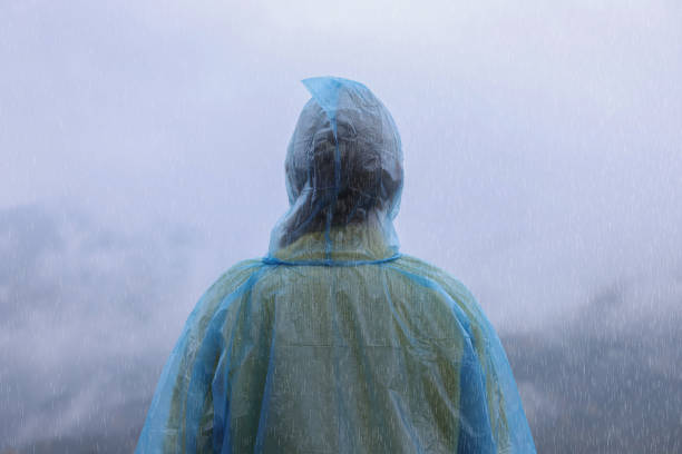 istock Woman in raincoat enjoying mountain landscape under rain, back view 1408200237