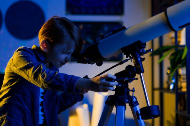 istock Smart inquisitive child explores sky through a telescope. 1408200261