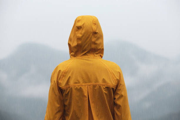 istock Woman in raincoat enjoying mountain landscape under rain, back view 1408200347