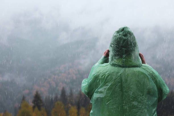 istock Woman in raincoat enjoying mountain landscape under rain, back view 1408200365