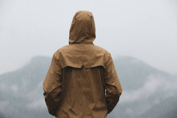 istock Woman in raincoat enjoying mountain landscape under rain, back view 1408200372