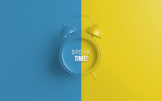 Alarm clock with Break Time written sign against blue and yellow background. Easy to crop horizontal composition for all your social media and print sizes with copy space.