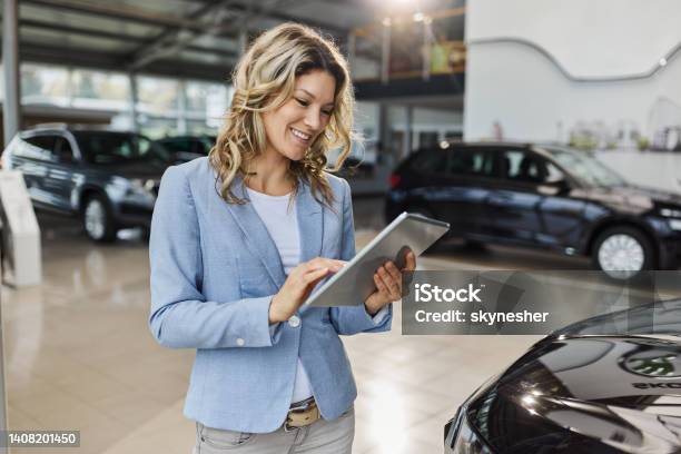 Happy Car Salesperson Using Digital Tablet In A Showroom Stock Photo - Download Image Now