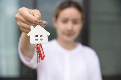 House key in hand, Female hand holding house key, real estate agent.