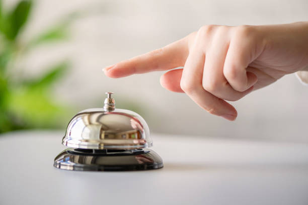 Hand of guest ringing in silver bell. reception desk with copy space. Hotel service. Selective focus stock photo