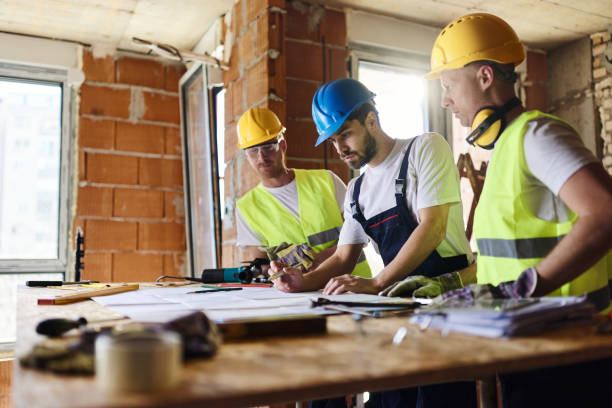 istock Team of manual workers examining housing project while working at construction site. 1408203240