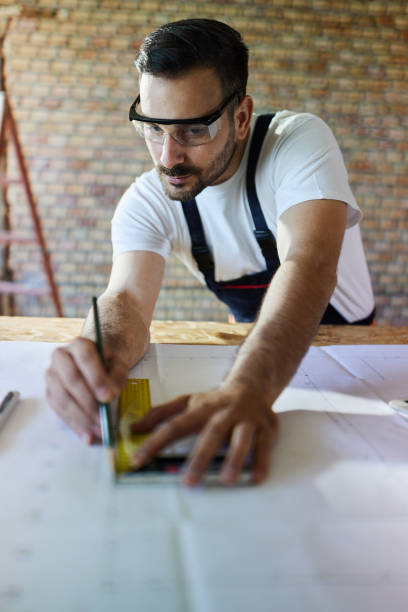 Concentrated construction worker drawing measurements during home renovation process.