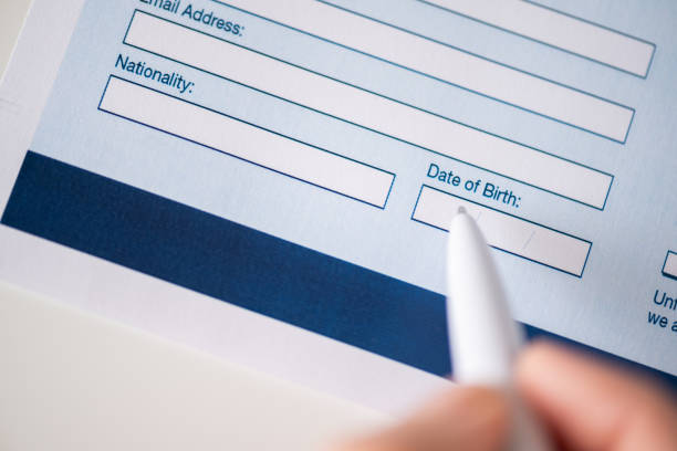 Woman customer filling property reservation form, date of birth, personal information,email, nationality on the table at the office. Close up. Selective focus. stock photo