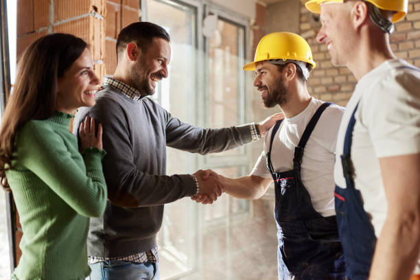 Happy manual workers came to an agreement with a couple at construction site. Happy construction workers came to a successful deal with their customers during home renovation process. building contractor stock pictures, royalty-free photos & images