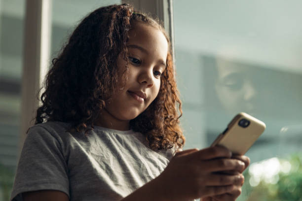 istock Cute little girl on her phone feeling happy 1408204732