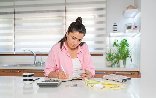 Woman Calculating Expenses On Kitchen