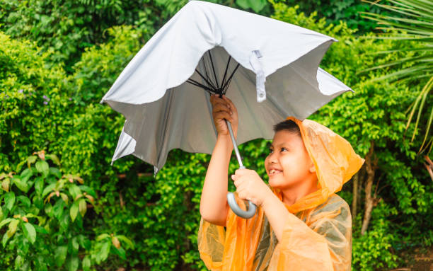 istock Asian boy puts on a raincoat and opens an umbrella on a rainy day. 1408205827
