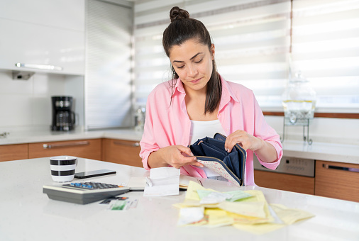 Woman With Empty Wallet And Utility Bills On Kitchen