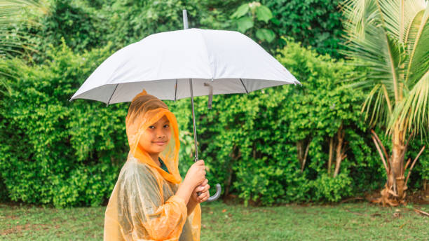 istock Asian boy puts on a raincoat and opens an umbrella on a rainy day. 1408207053