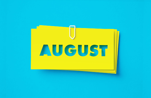 August written cut out yellow adhesive notes sitting on blue background. Horizontal composition with copy space.