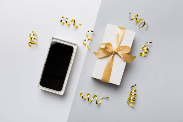 istock Opened gift box with gold ribbon and smartphone on color background, top view. Blank open box packaging mockup , Template for your design - branding mockup 1408209915