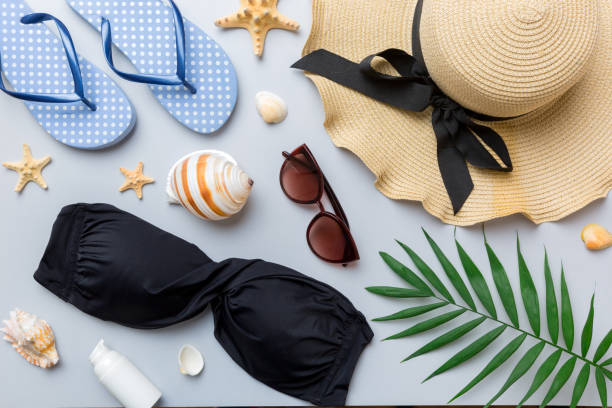Woman swimwear and beach accessories flat lay top view on colored background Summer travel concept. bikini swimsuit, straw hat and seasheels. Copy space Top view.