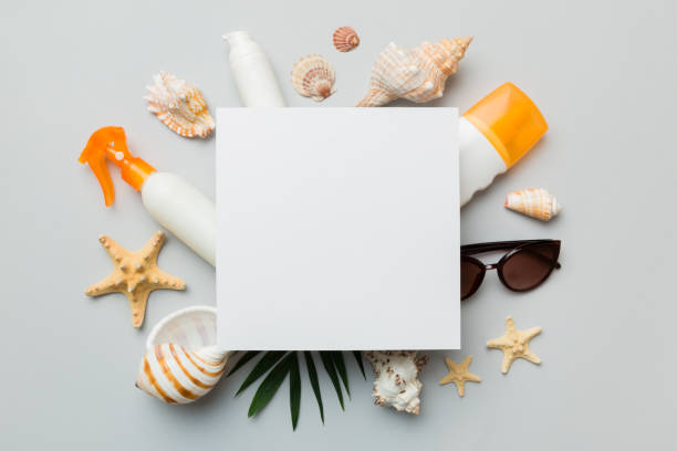istock Summer time concept with blank greeting card and blank white paper on colored background. Seashells from ocean shore in the shape of frame separated with space for text top view 1408210849