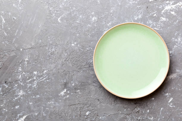 istock Top view of empty green plate on cement background. Empty space for your design 1408210876