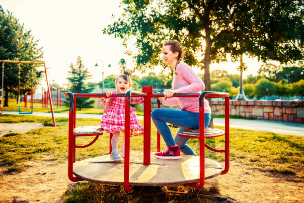 istock Single mother playing with her daughter on the park carousel 1408211929