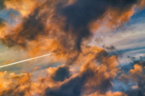 A single plane crosses stunning golden clouds at sunset. The clouds look like they were painted.