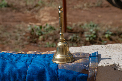 Stock photo of carved designer copper or bronze bell or hand bell used for worshiping god in hindu temples. bell kept on wall under bright sunlight at Kolhapur, Maharashtra, India. focus on object.