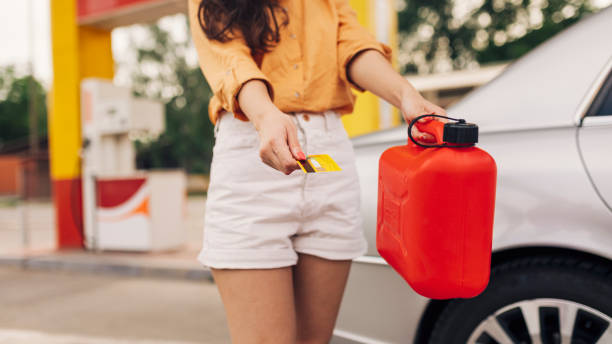 ガソリンスタンドのガソリン缶とクレジットカードを持つ女性のクローズアップ - gasoline car buying fuel pump ストックフォトと画像