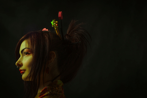 Pretty asian woman in kimono posing over dark background