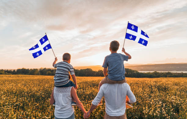 Patriotic family waving Quebec flags on sunset
