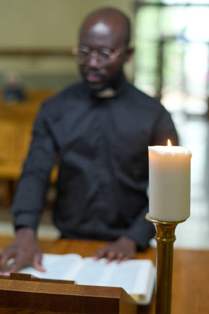 istock White candle burning against young African American pastor reading Bible 1408224320